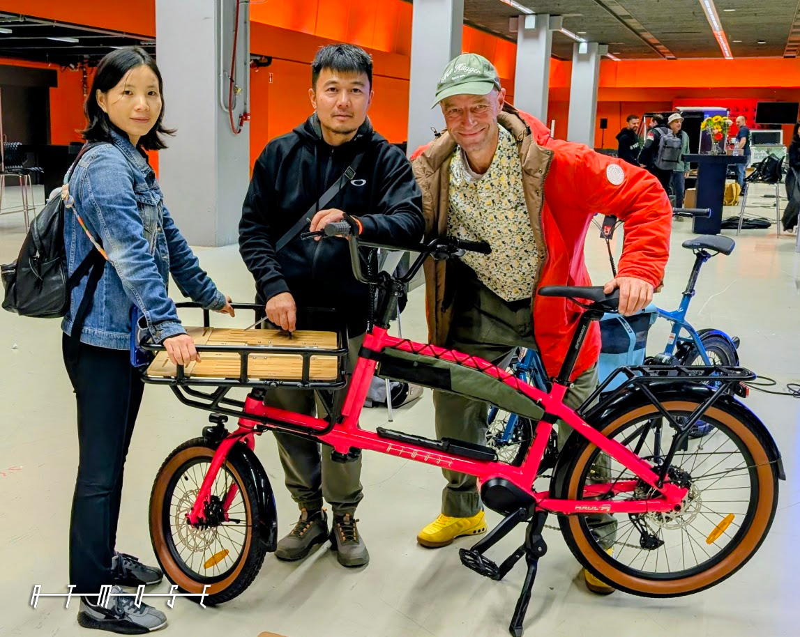 Three people with an ATMOSE cargo bike on the exhibition stand at ICBF 2026